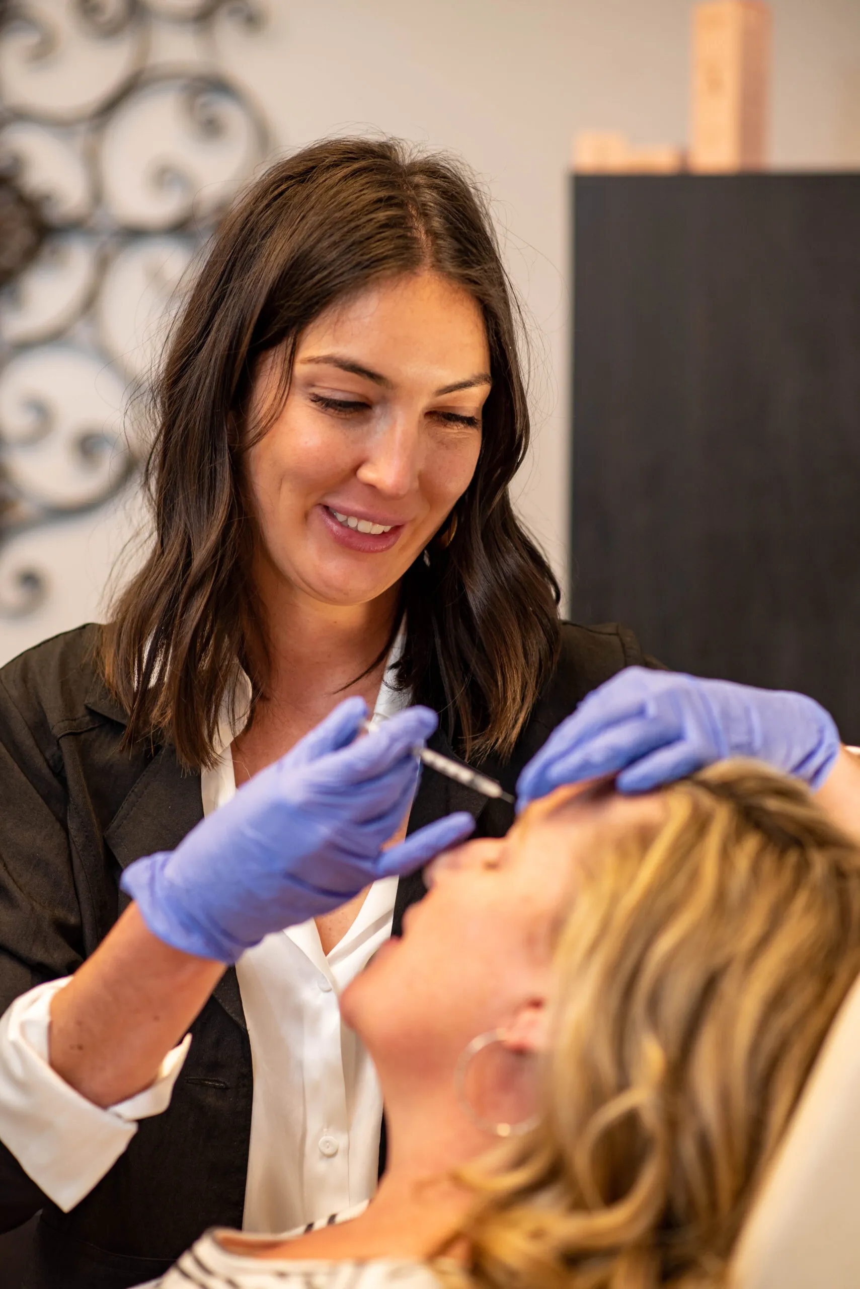 Woman injecting cosmetic filler into forehead