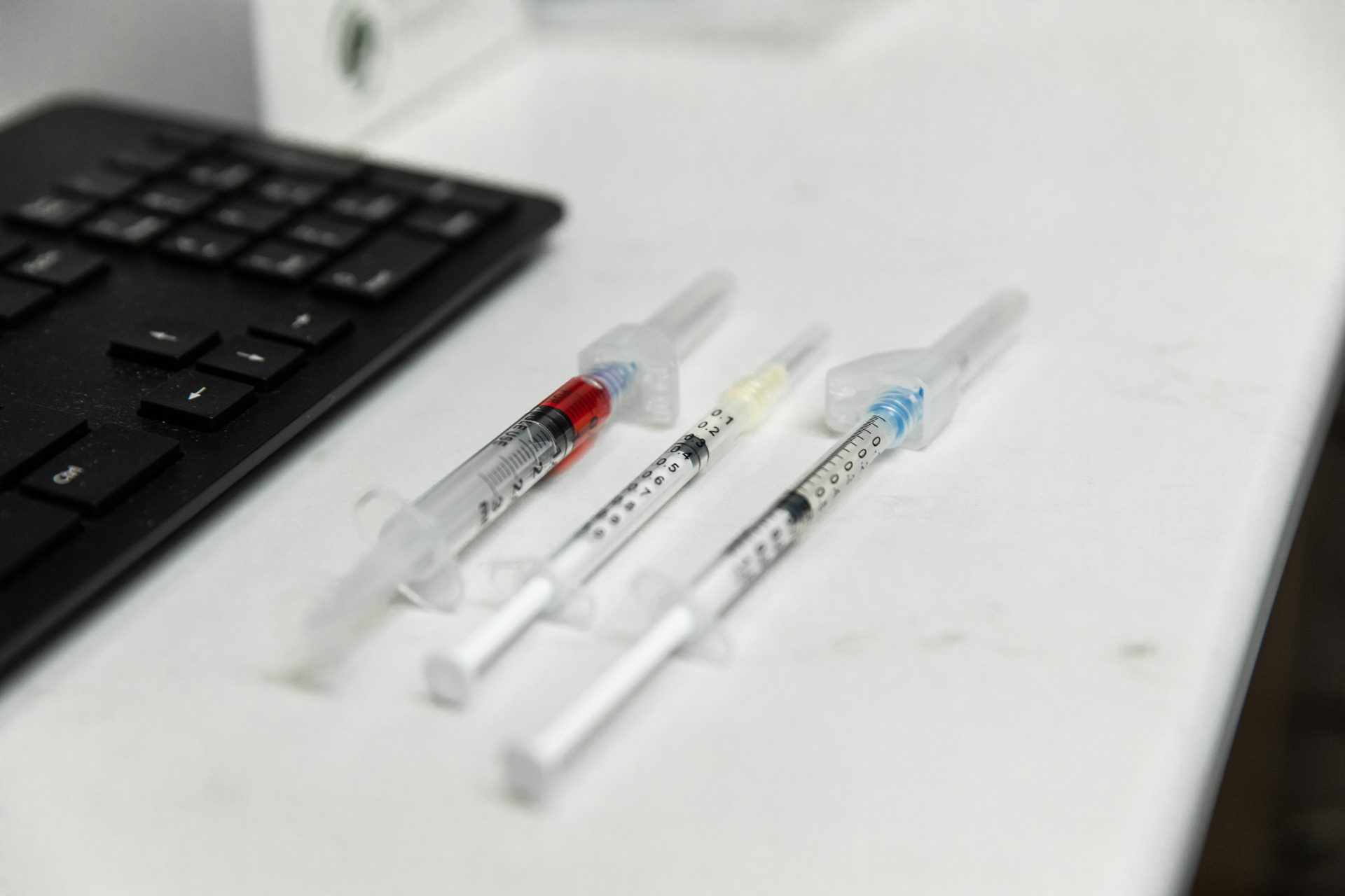 Three syringes placed beside computer keyboard