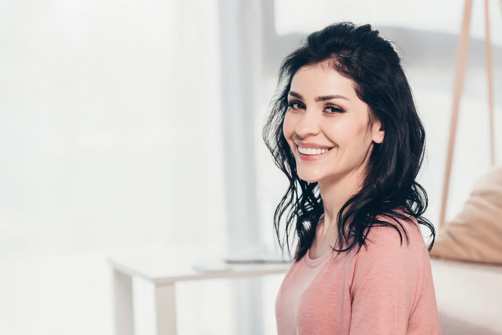 Smiling woman in pink shirt indoors