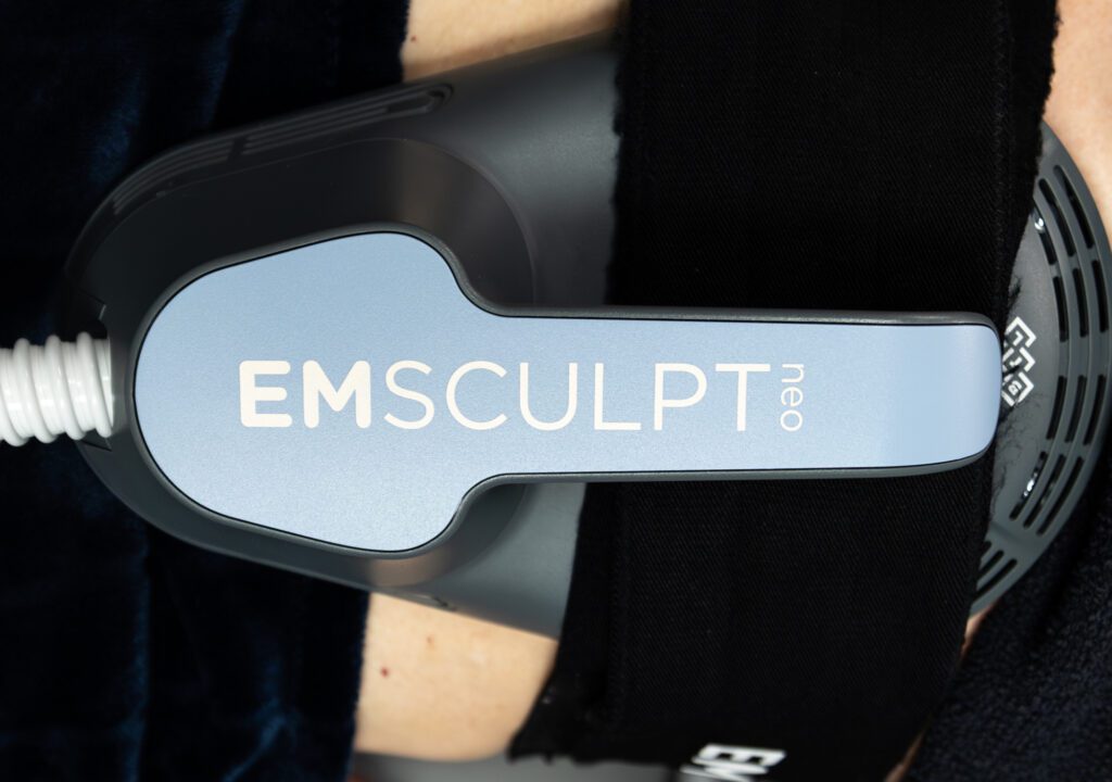 A patient lies down with an Emsculpt NEO paddle attached to their abdomen as a form of functional medicine in Fort Collins.
