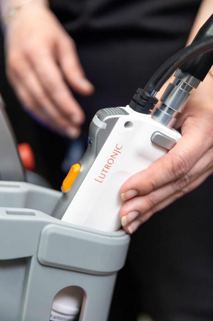 Hand holding Lutronic laser treatment device.