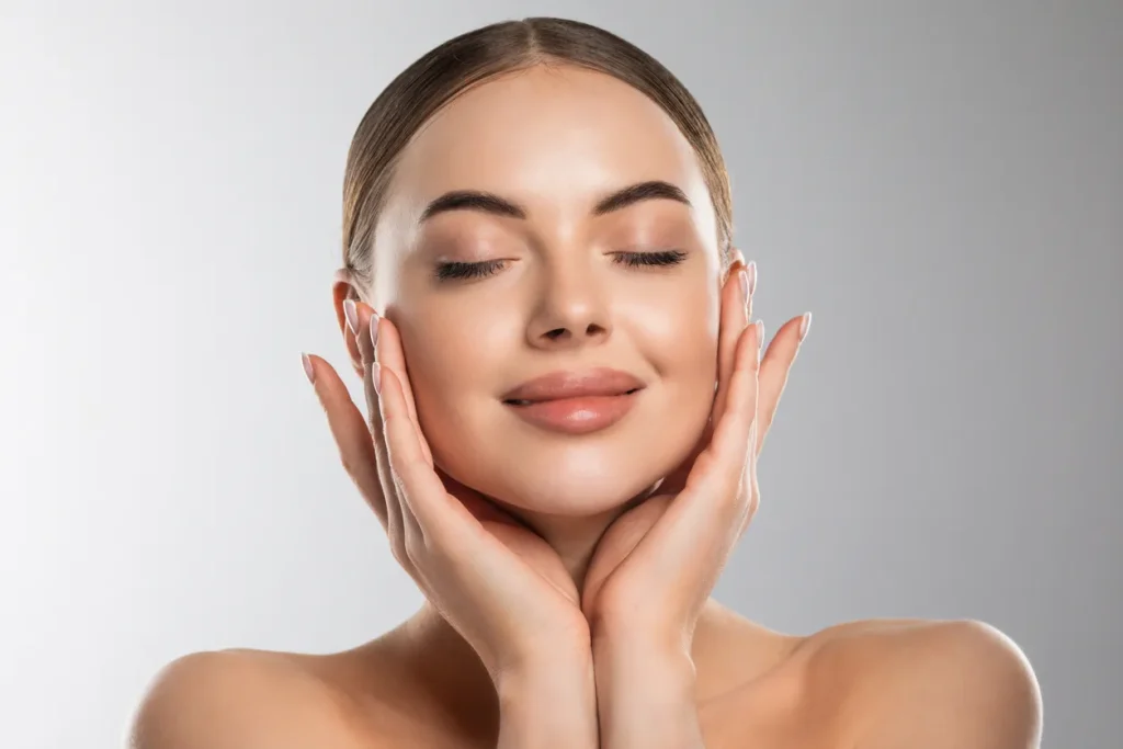 Woman smiling with hands gently on face.