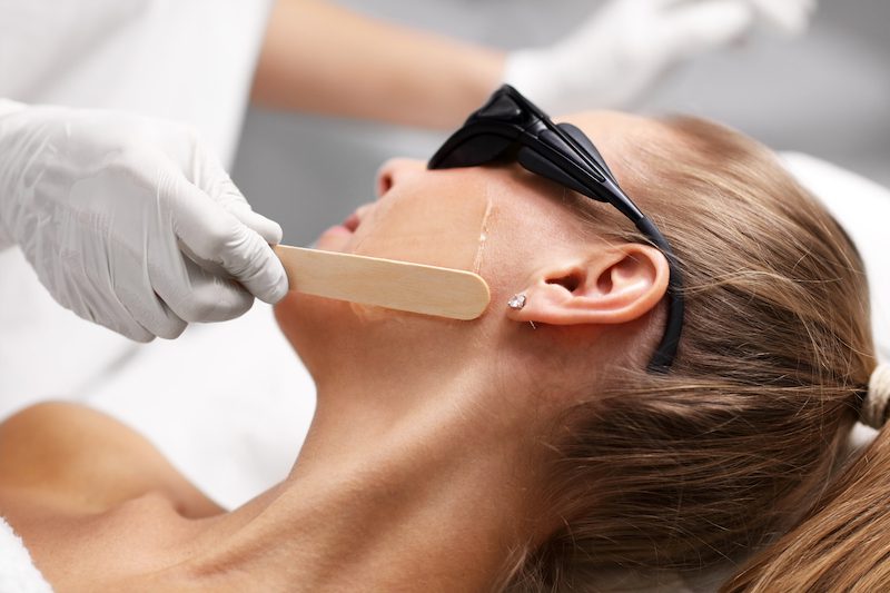 A woman is waxing her face at Xanadu after learning about facial hair removal in Fort Collins.