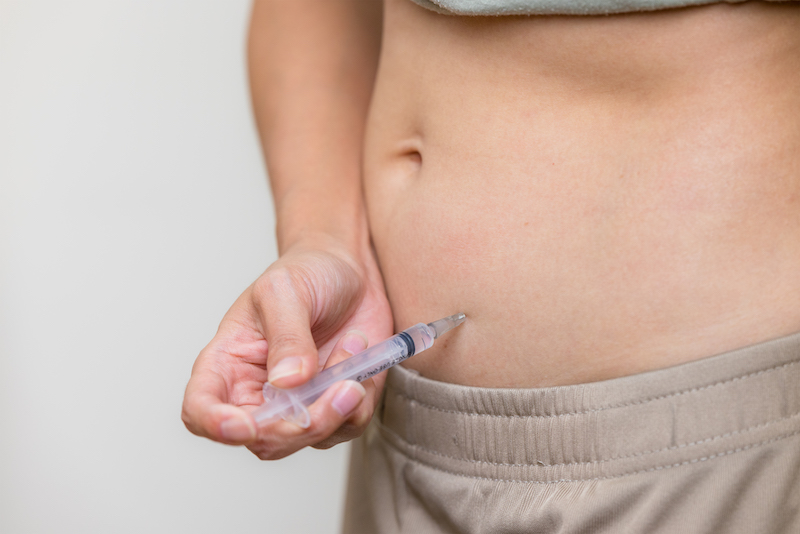 A woman is injecting a syringe into her abdomin with a semaglutide injection from Xanadu weight loss clinic 