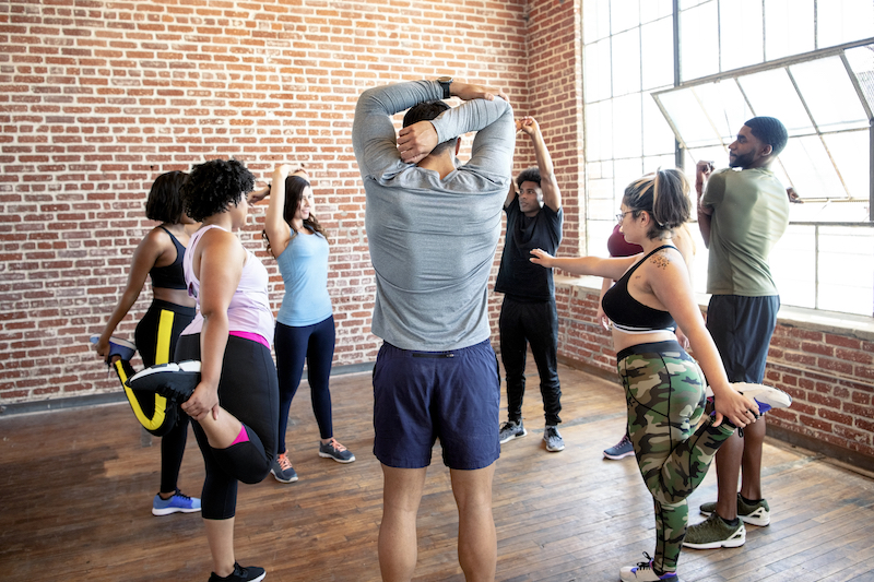 A group exercise class is stretching before their workout, which is important to include in your plan for weight loss injections in Fort Collins.